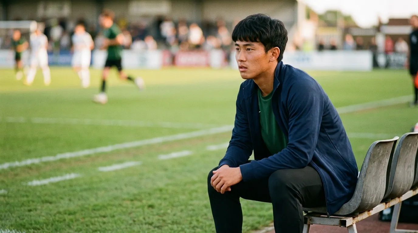 ジャンパーを羽織り、ベンチから試合を見ている選手